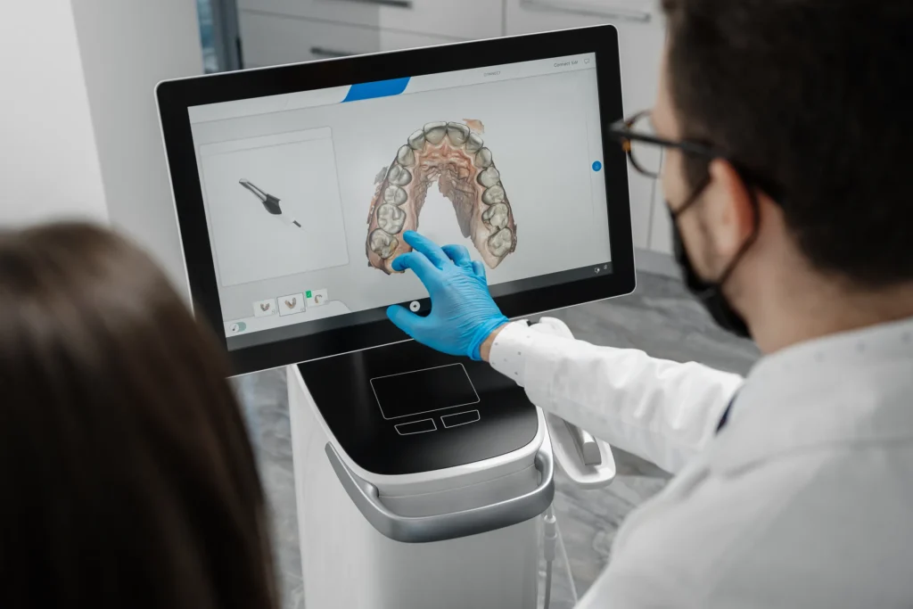 Dentist pointing at a 3D scan of a patient’s teeth on a monitor