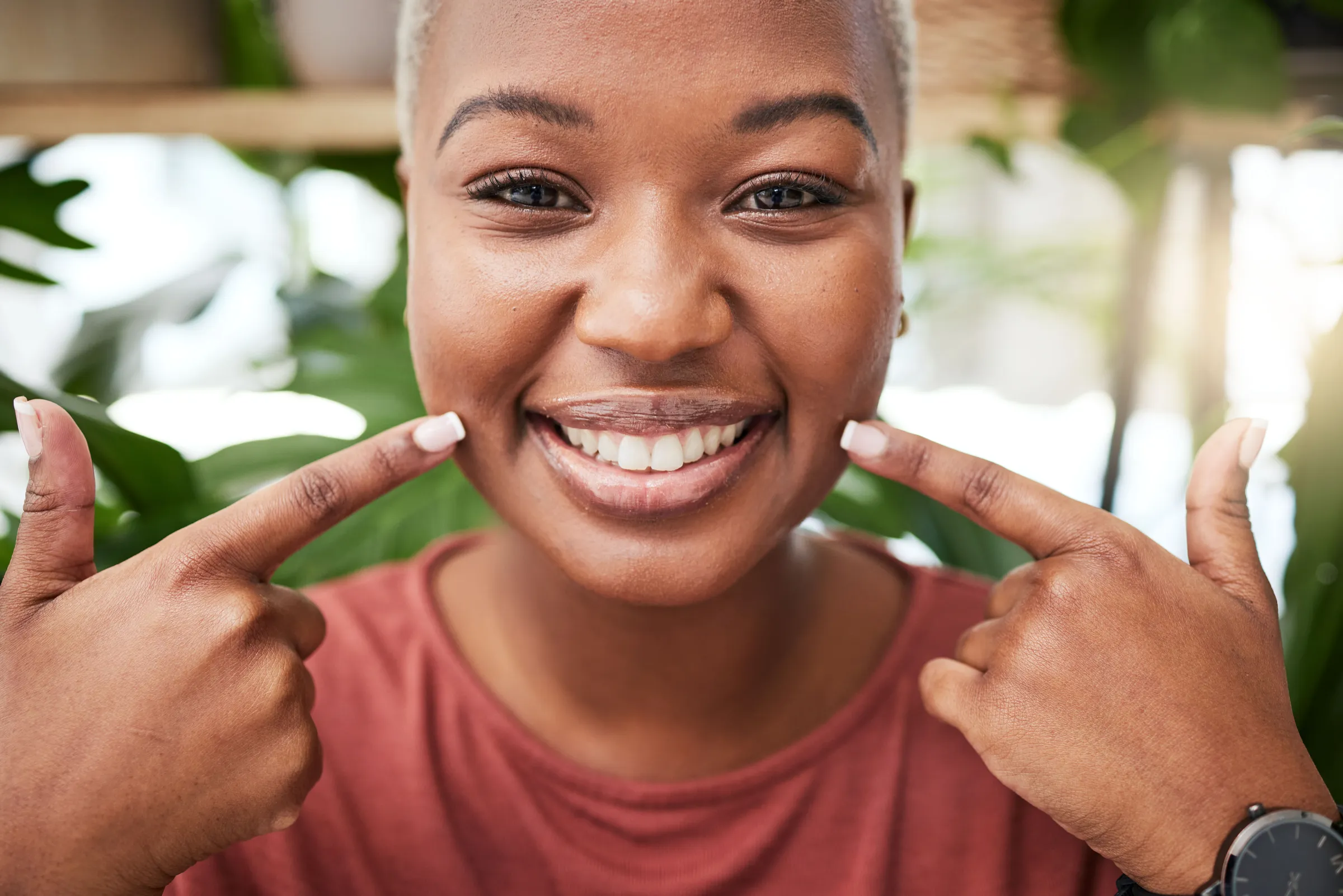 Smiling woman pointing to her teeth with both hands