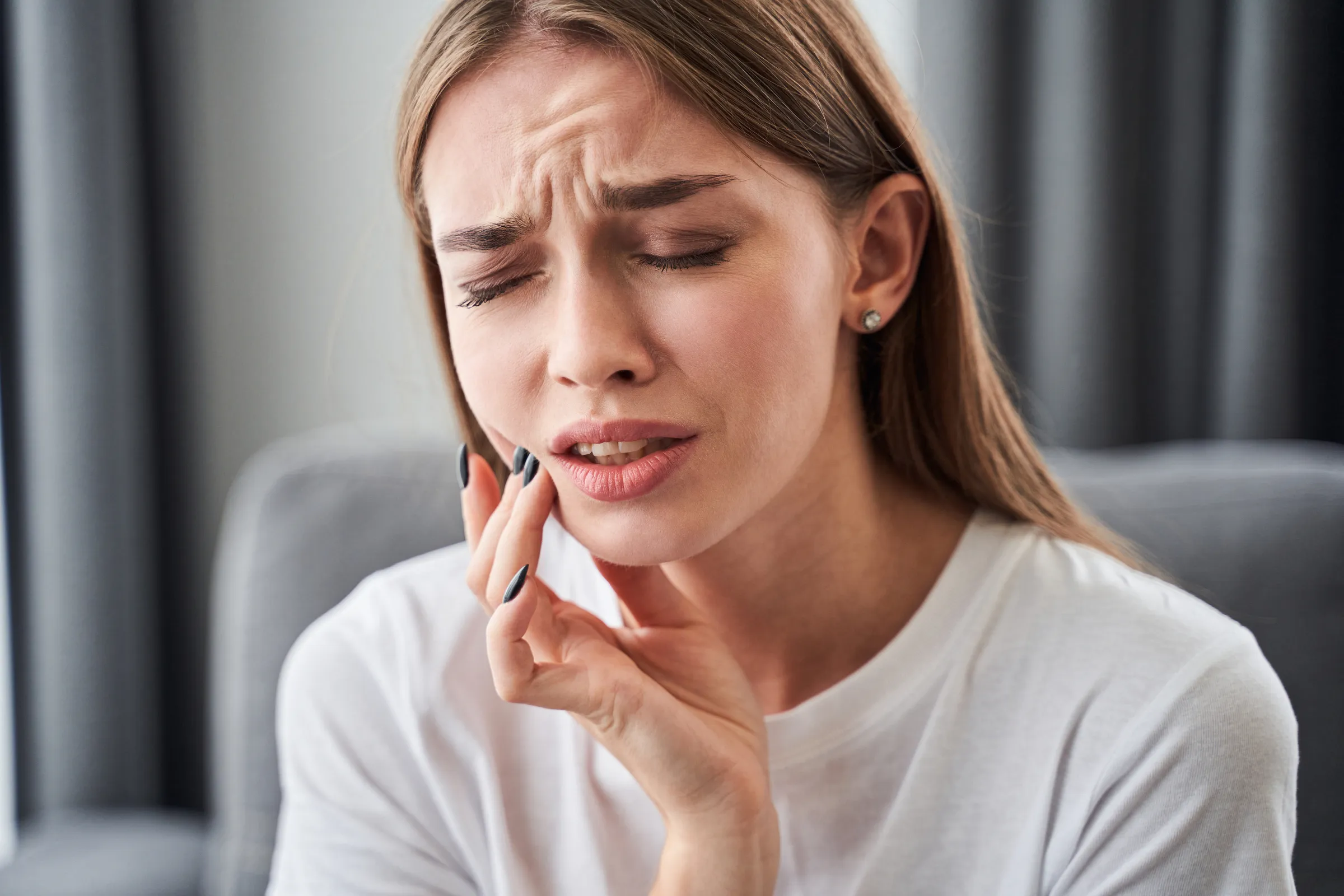 Woman holding her cheek in pain from a toothache