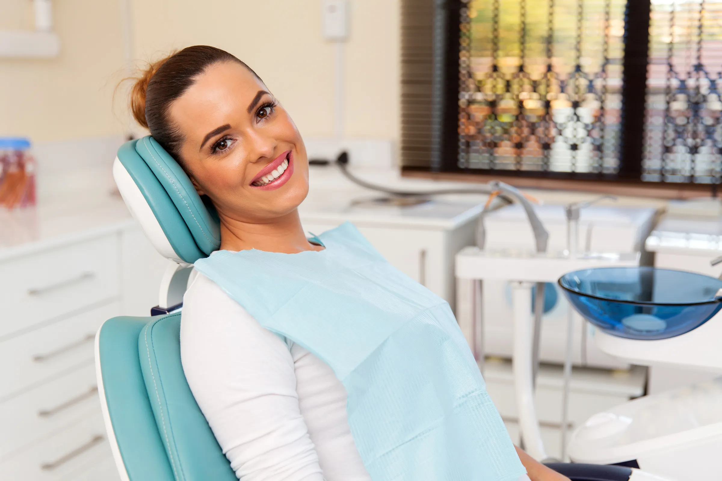 Smiling woman seated in a dental chair in a bright treatment room