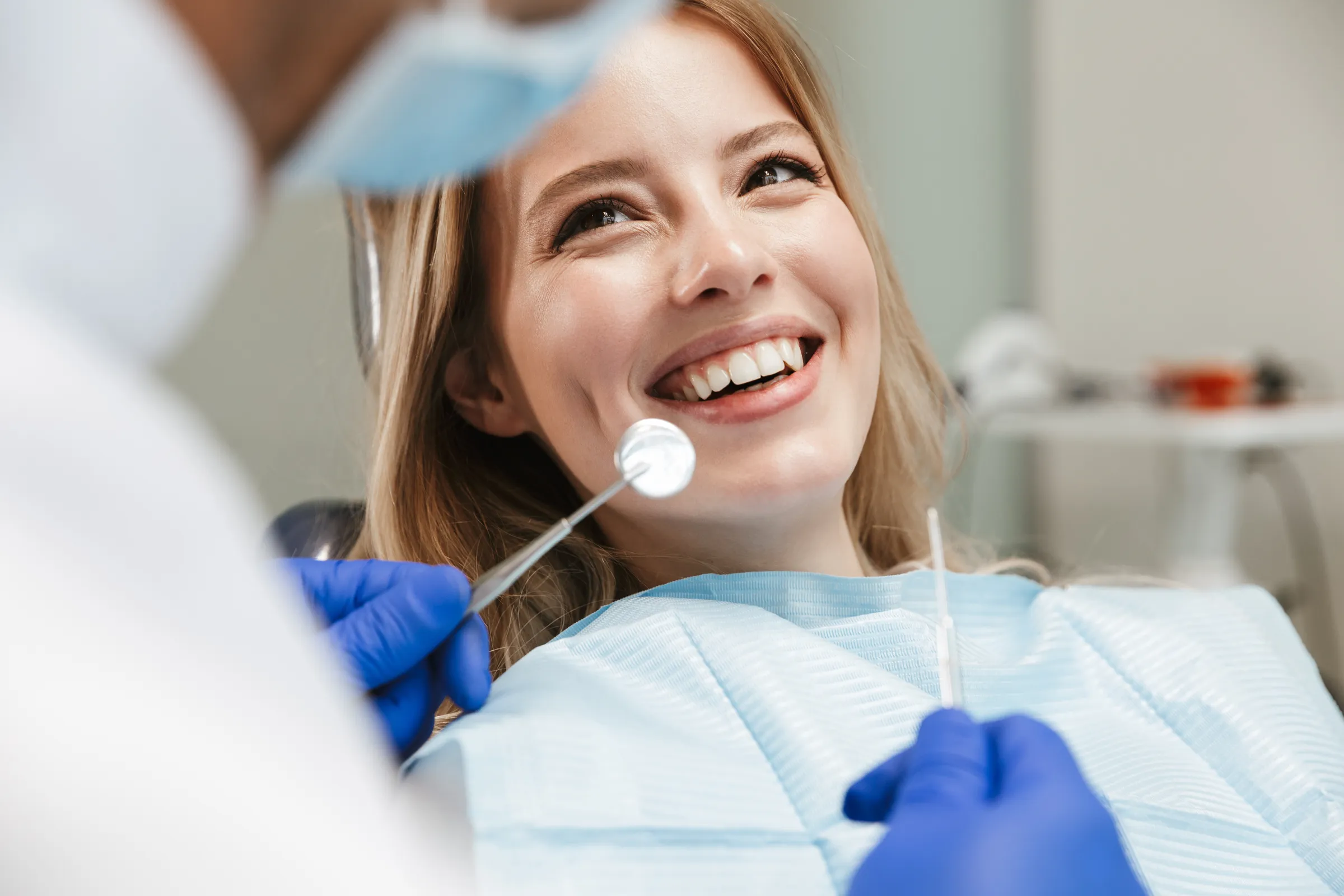 Smiling woman during a dental checkup with a mirror and probe