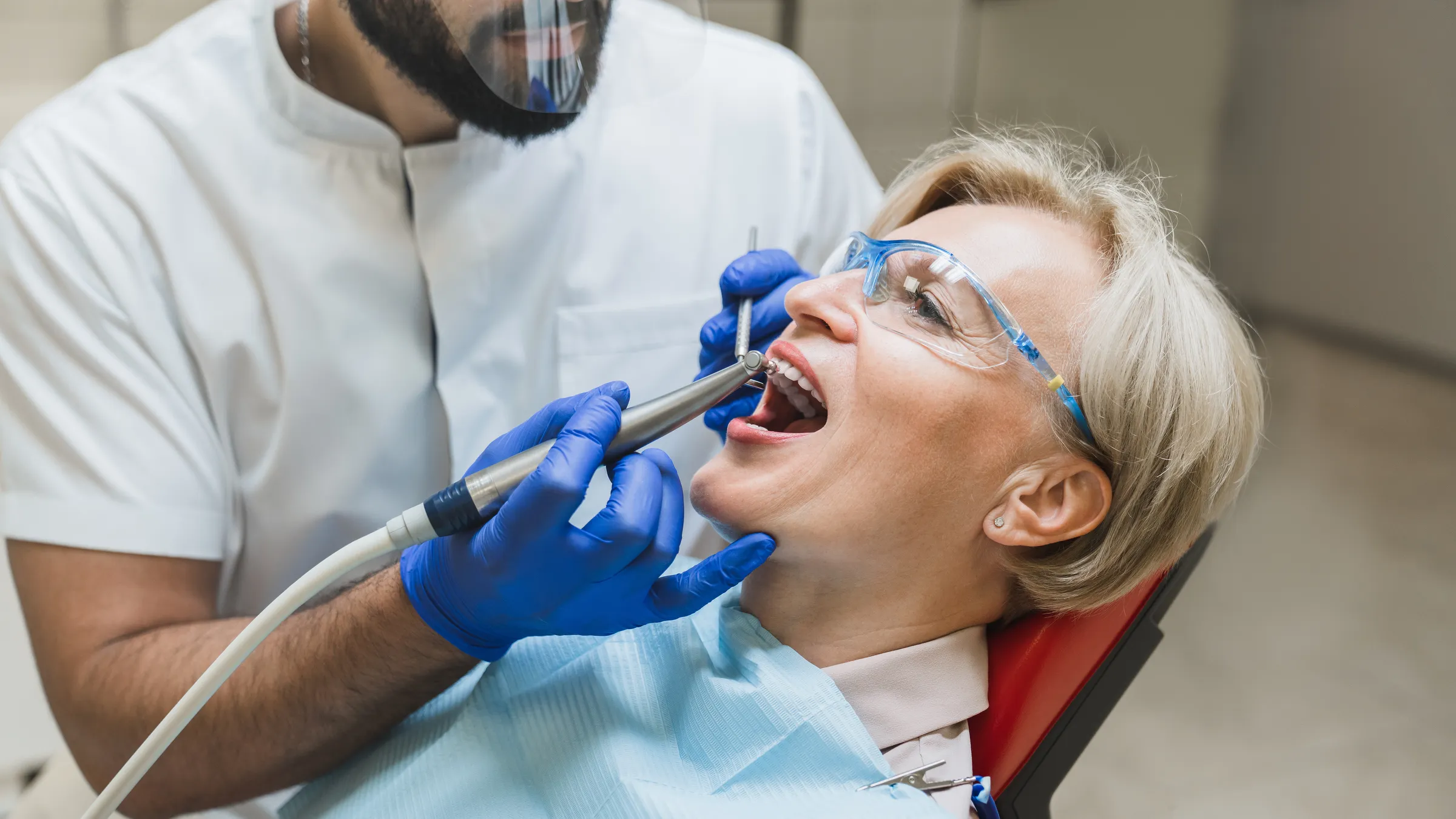 Dentist treating an older woman wearing protective glasses