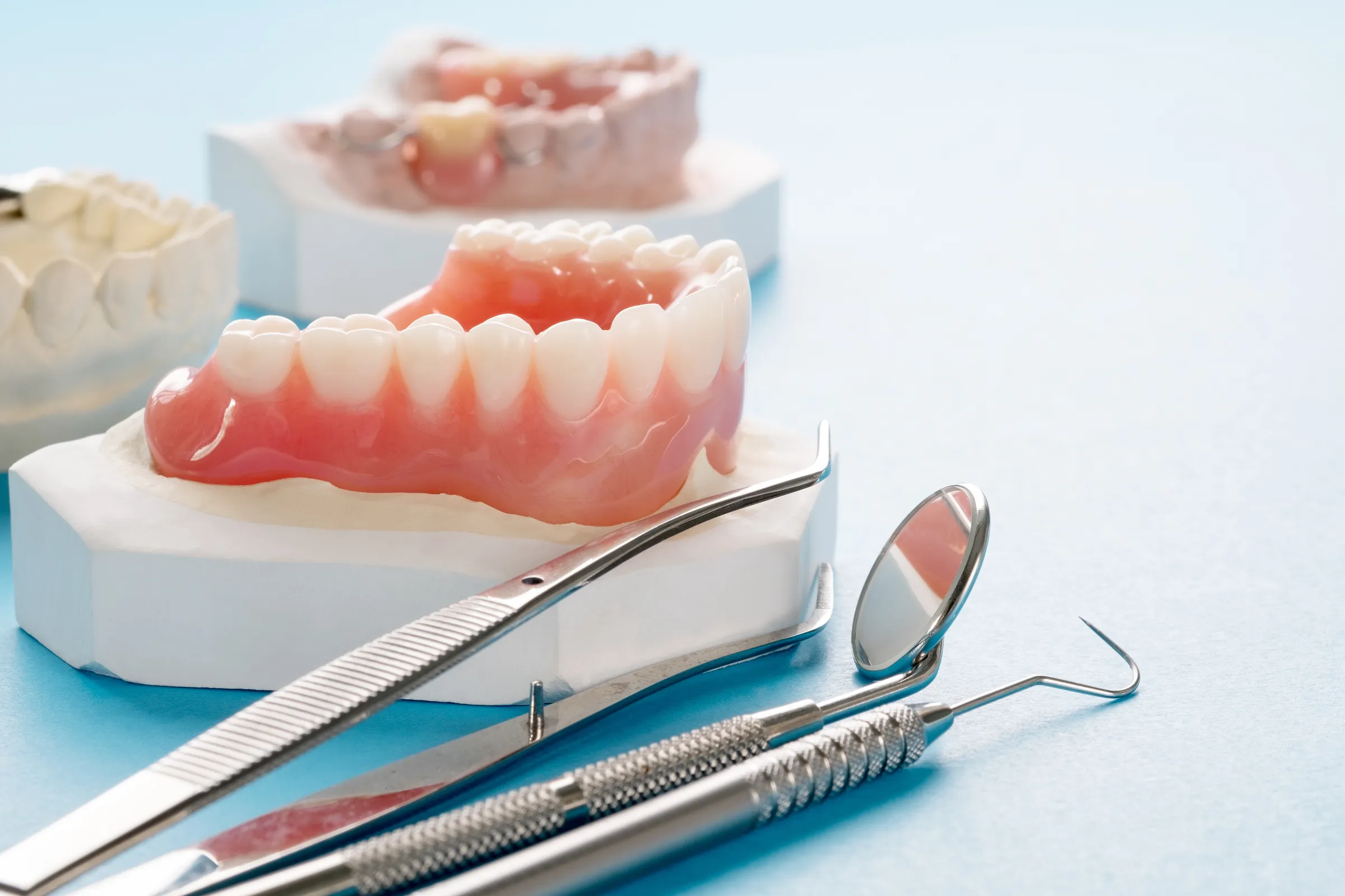 Full dentures and dental instruments on a light blue table