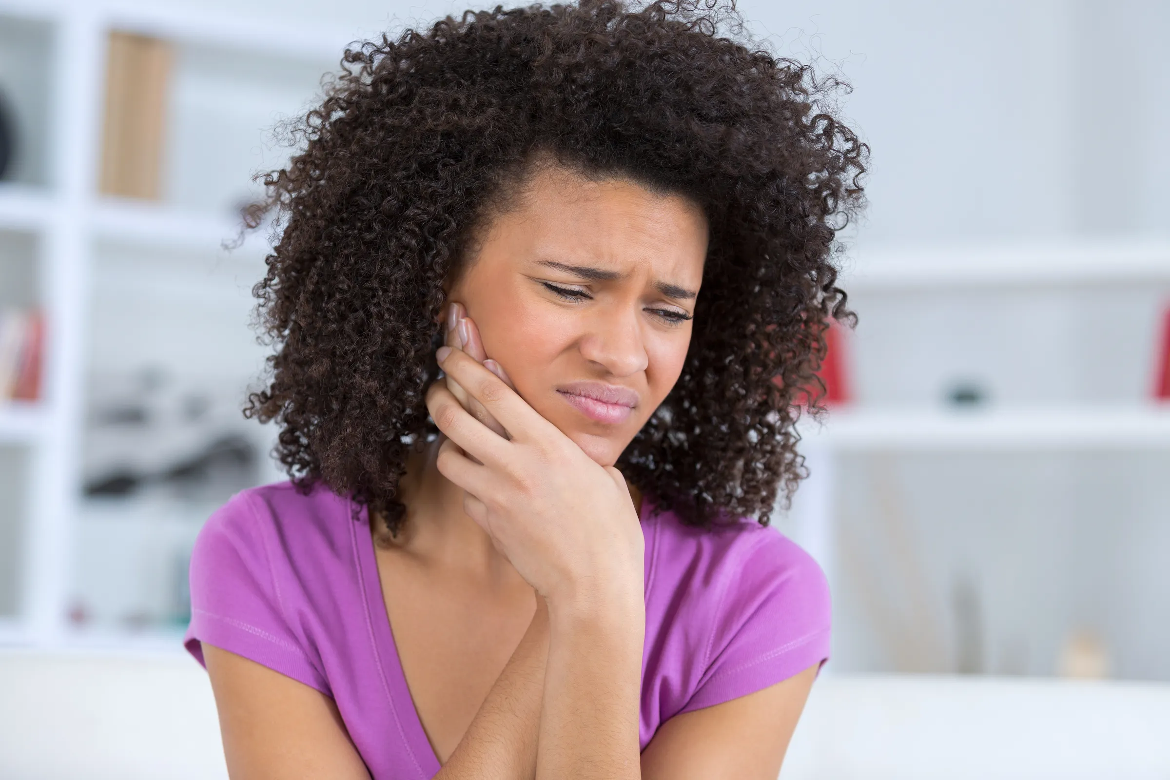 Woman holding her jaw in pain from a dental emergency