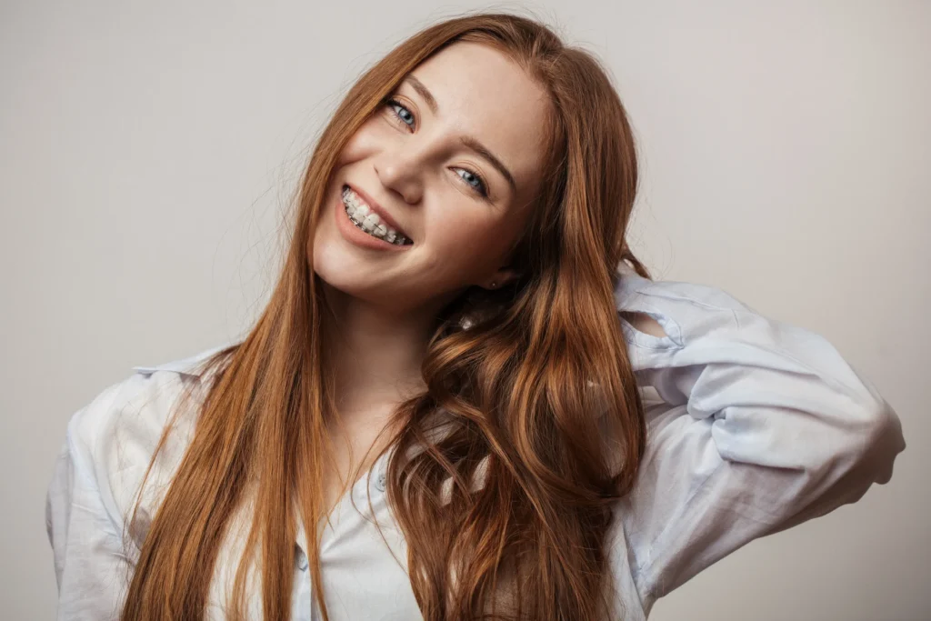 Smiling young woman with braces touching her hair