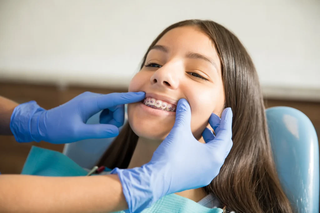 Dentist checking a smiling teenage girl’s braces