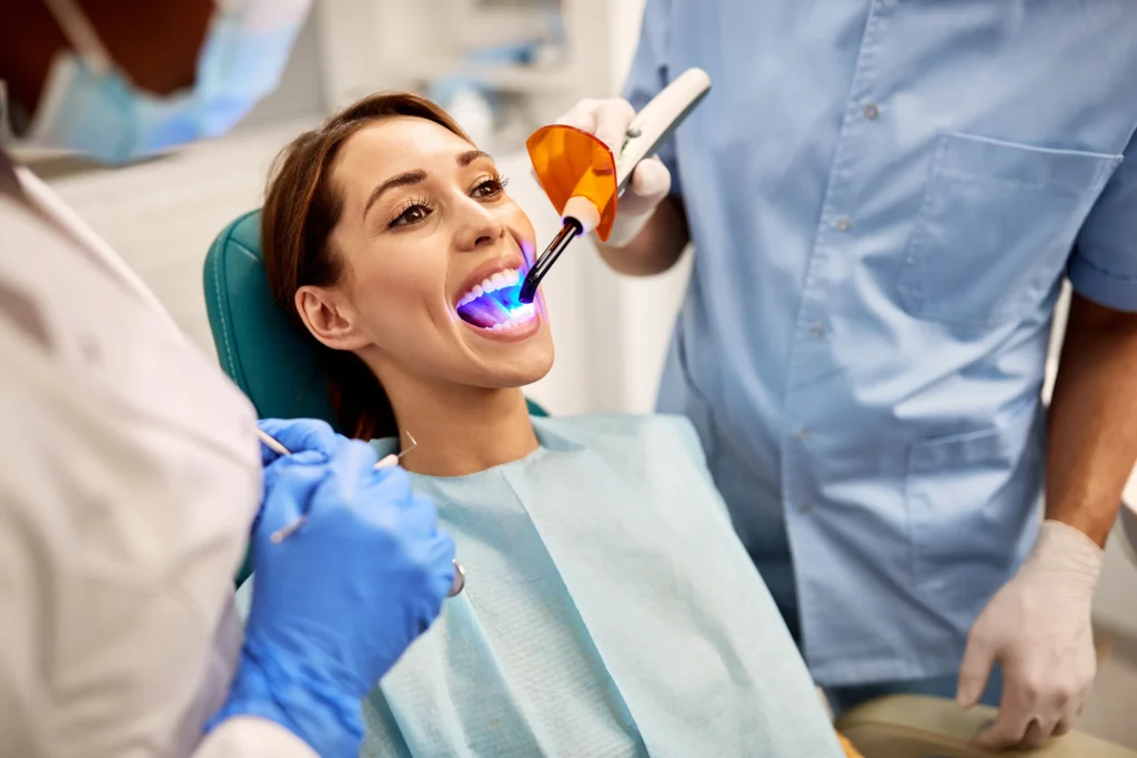 Dentist curing a filling with a blue light as the patient smiles