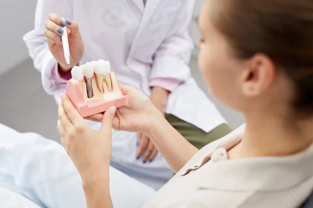 Patient looking at a dental implant model during a consultation