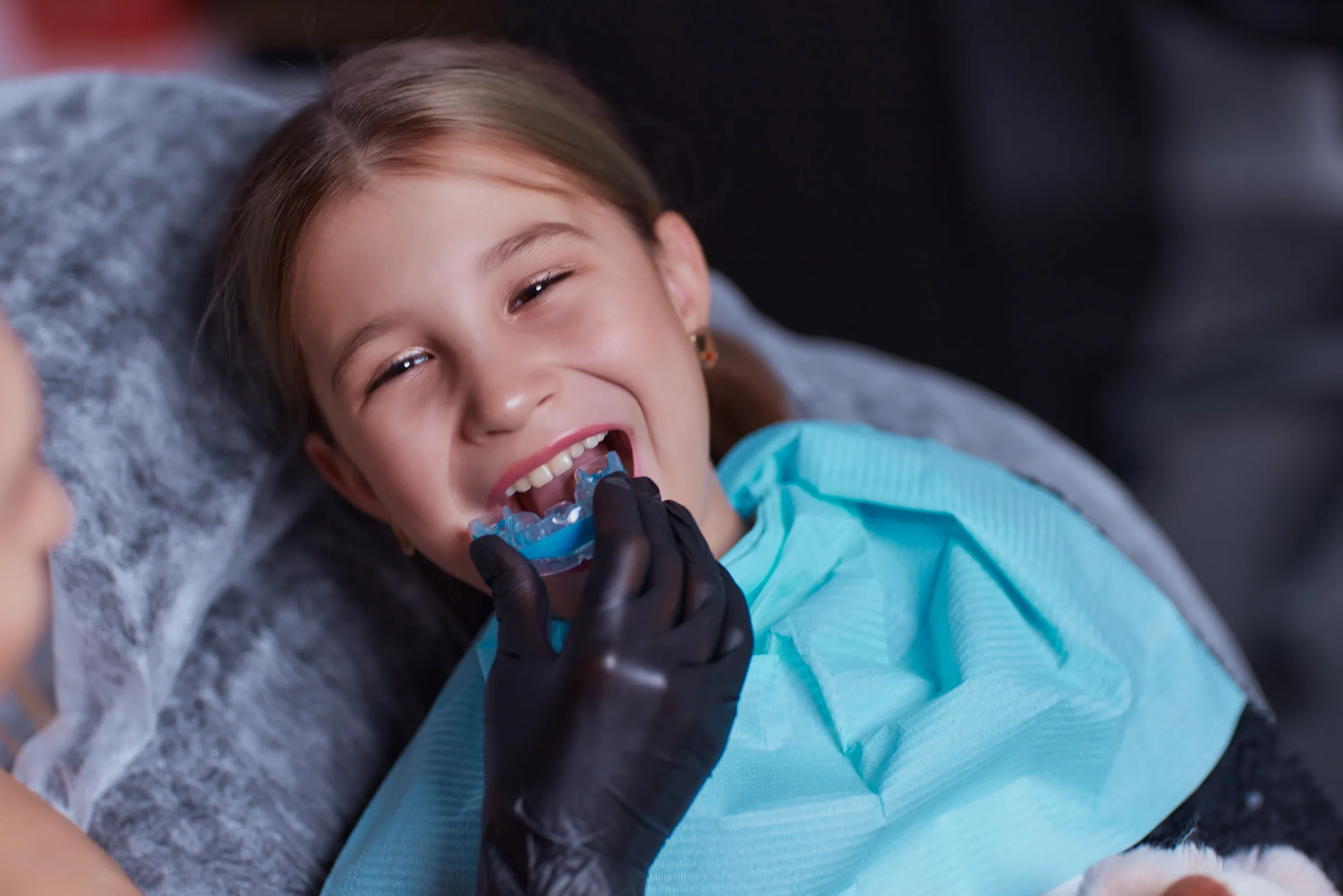 Smiling girl in a dental chair being fitted with a mouth guard