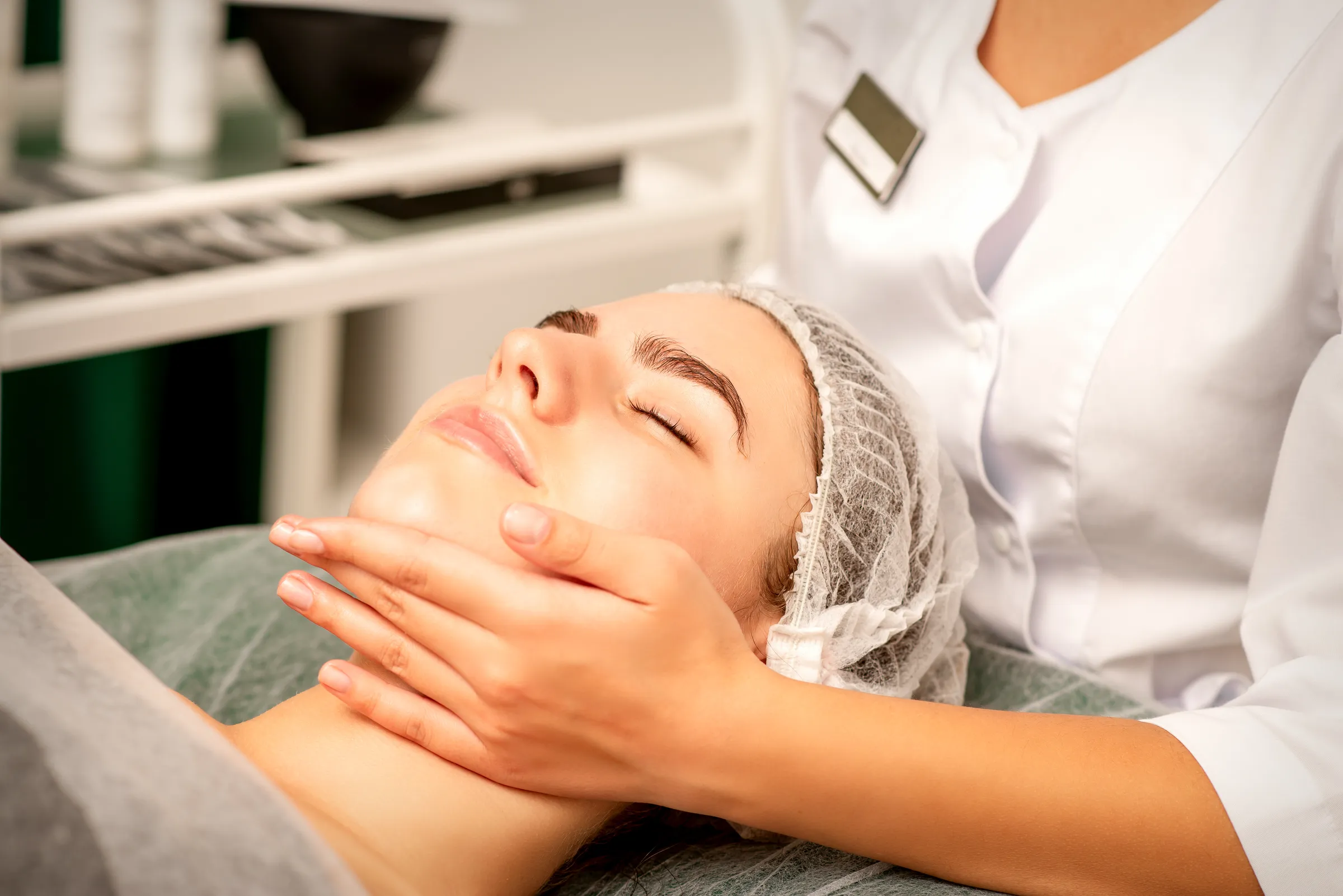 Therapist gently massaging a relaxed woman's jaw