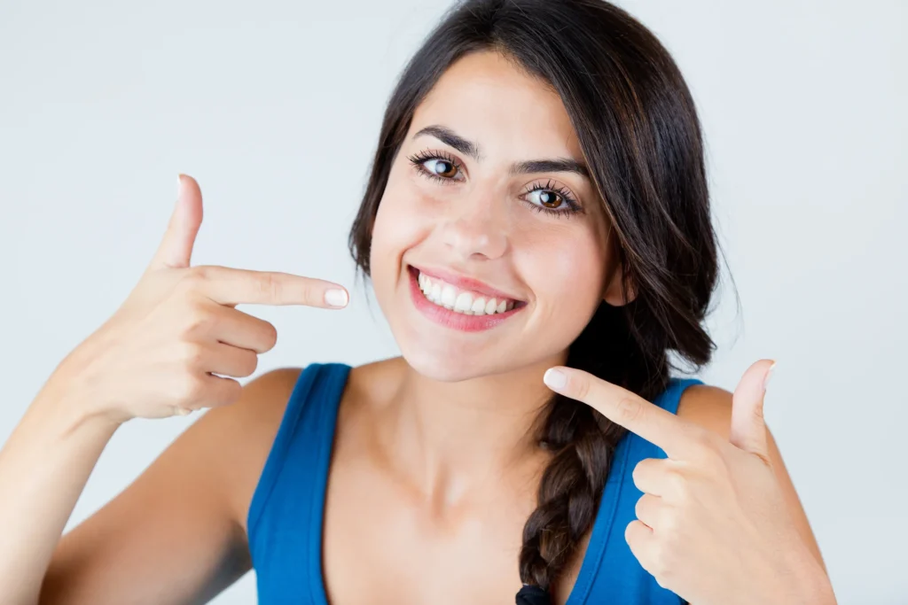Smiling woman pointing at her white teeth