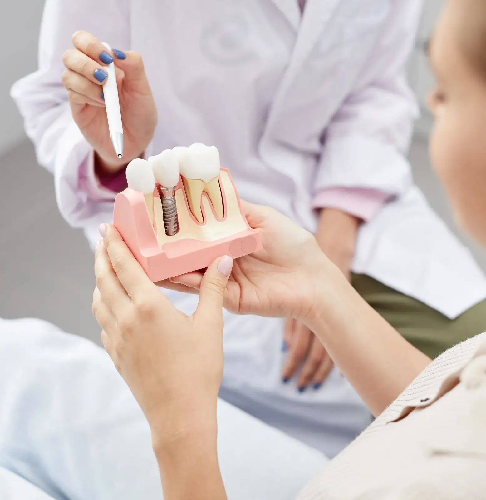 Patient looking at a dental implant model during a consultation