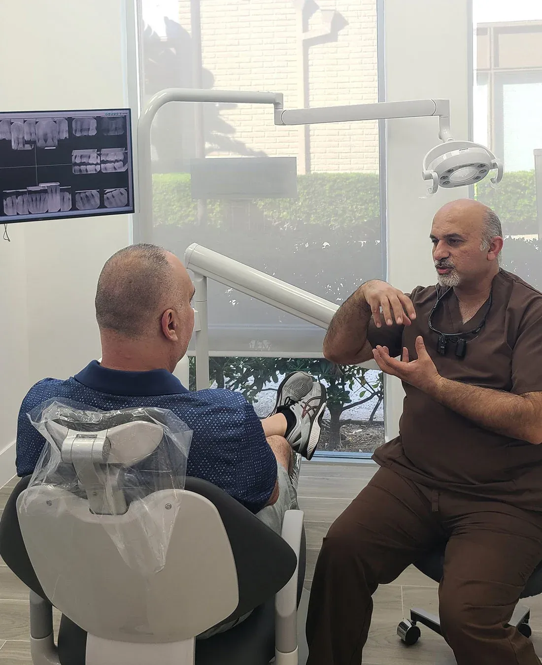 Dr. Haroonian talking with a patient in the treatment chair