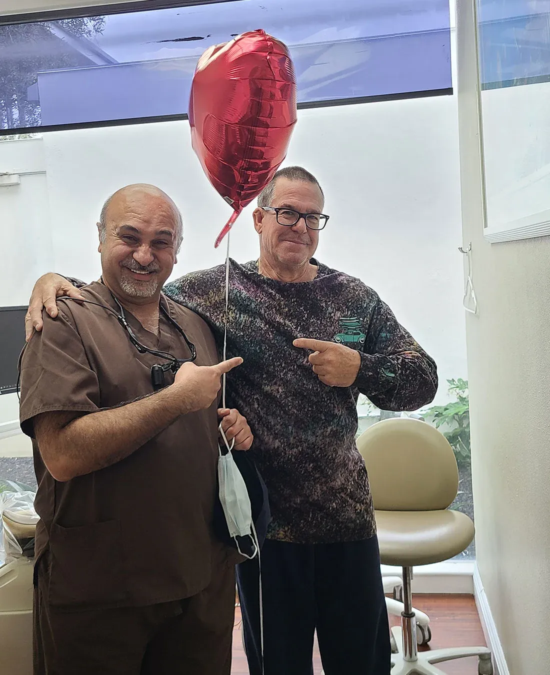 Dr. Haroonian and a patient celebrating with a heart balloon