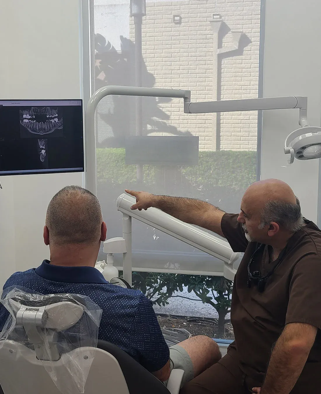 Dr. Haroonian pointing out an X-ray on the treatment room monitor